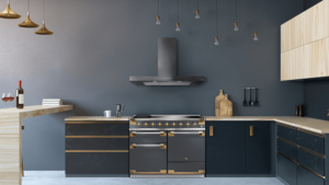 A Falcon Elise Luxe 110 Range Cooker in gun metal gray with brass trim sits in a modern kitchen with gray walls gold handing lights and black and light wood cabinetry.